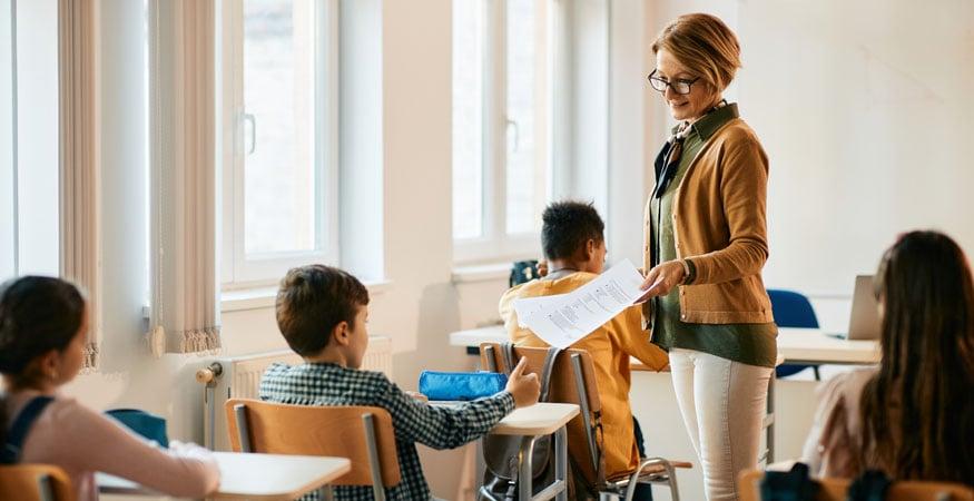 Teacher giving paper tests to students