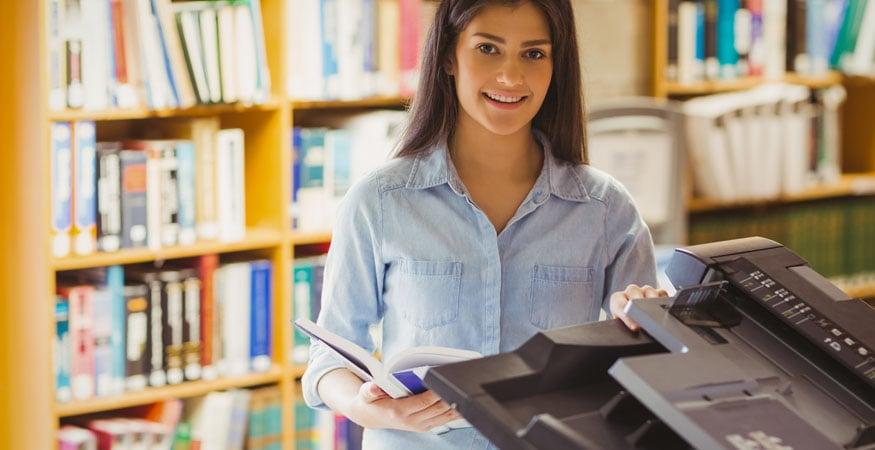 Woman copying pages from a book at the library