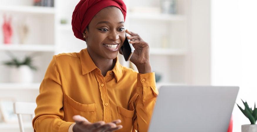 woman talking on cell phone and working on a laptop