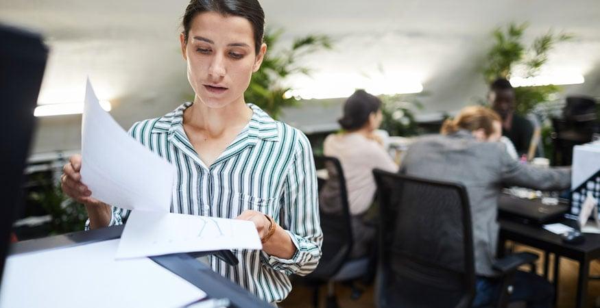 Woman with paperwork at a digital scanner