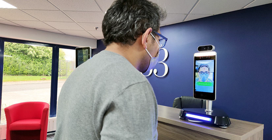 man in mask talking with woman on tablet