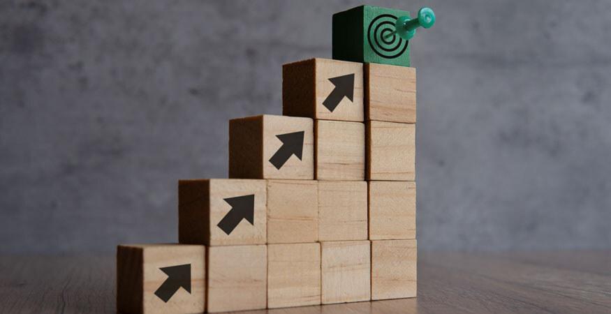 Wooden blocks stepping upward with a green target at the top