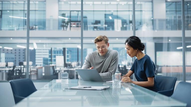 two people at table working on laptop