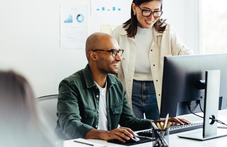 Woman helping man on desktop computer in an office